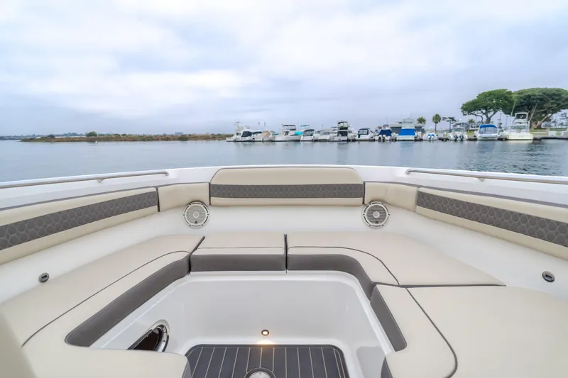  Yacht Photos Pics 2018 Pursuit boat interior with cushioned seating, overlooking a marina with docked boats.
