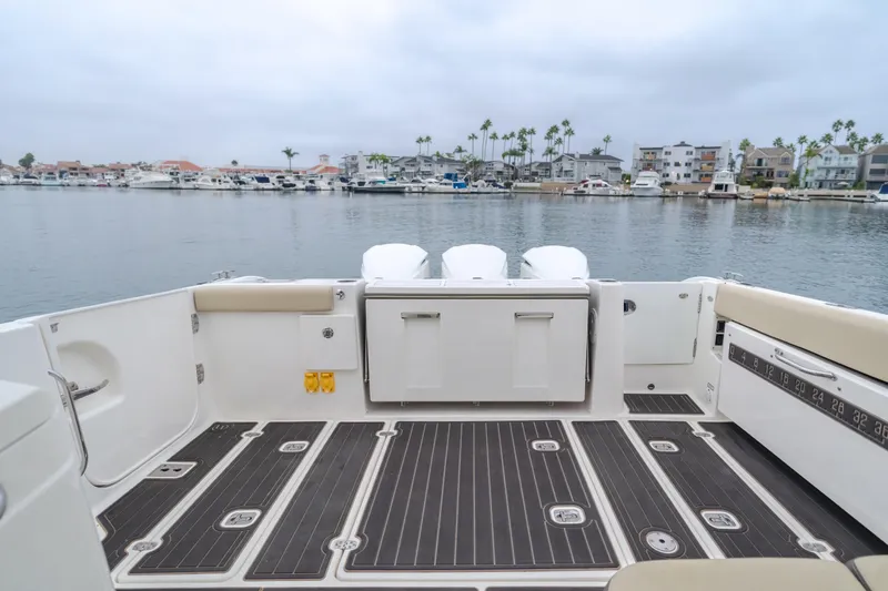  Yacht Photos Pics 2018 Pursuit boat deck with seating, overlooking a marina with palm trees and boats.