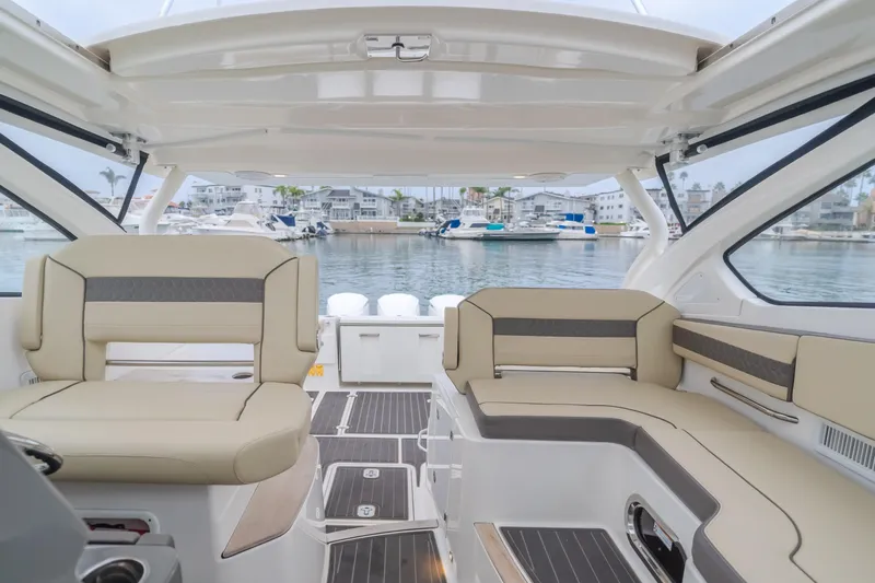  Yacht Photos Pics Interior of a 2018 Pursuit boat with beige seating, overlooking a marina.