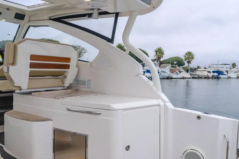  Yacht Photos Pics 2018 Pursuit boat interior with seating and storage, docked at a marina with palm trees.