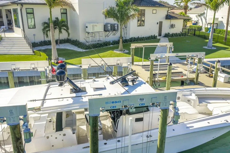 Best Deal Yacht Photos Pics 2023 HCB 53 Suenos RXV docked near a modern waterfront home with palm trees.
