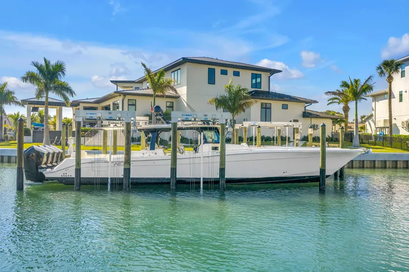 Best Deal Yacht Photos Pics 2023 HCB 53 Suenos RXV boat docked near luxury waterfront homes.