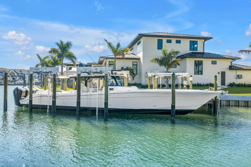 Best Deal Yacht Photos Pics 2023 HCB 53 Suenos RXV boat docked by a modern waterfront home.