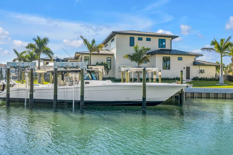 Best Deal Yacht Photos Pics 2023 HCB 53 Suenos RXV boat docked by a modern waterfront home.