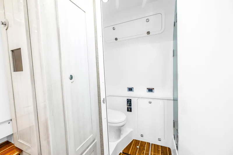 Best Deal Yacht Photos Pics 2023 HCB 53 Suenos RXV boat bathroom with sleek white interior and wooden flooring.