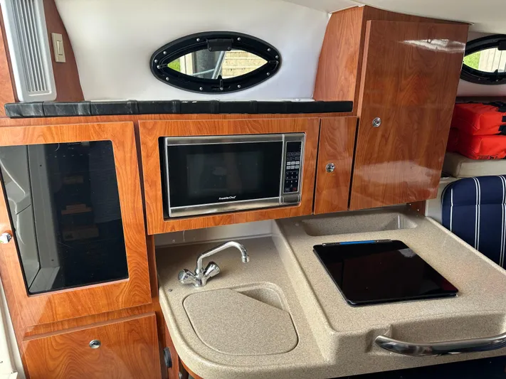 Last One II Yacht Photos Pics Interior of 2015 Wellcraft 290 Coastal boat with kitchenette, microwave, and sink.