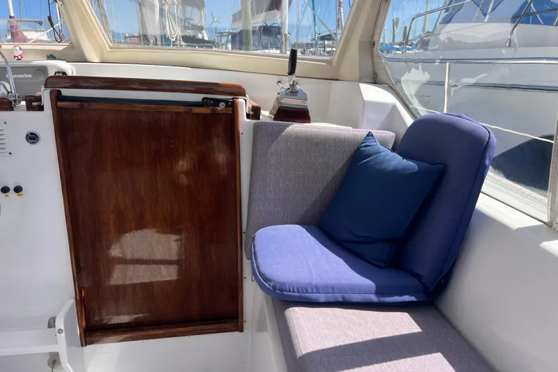 Hobo Tiempo Yacht Photos Pics Cozy seating area on 1986 Amel Mango yacht with blue cushions and wooden panel.