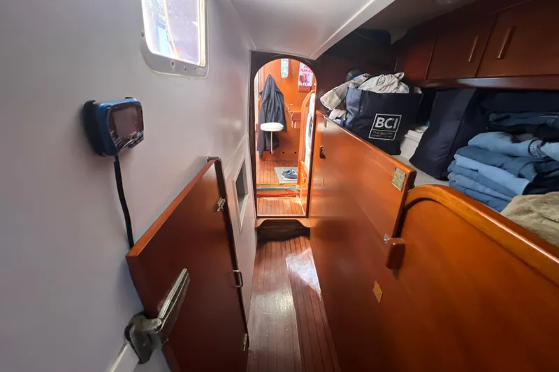 Hobo Tiempo Yacht Photos Pics Interior of 1986 Amel Mango sailboat with wooden cabinetry and neatly stacked linens.