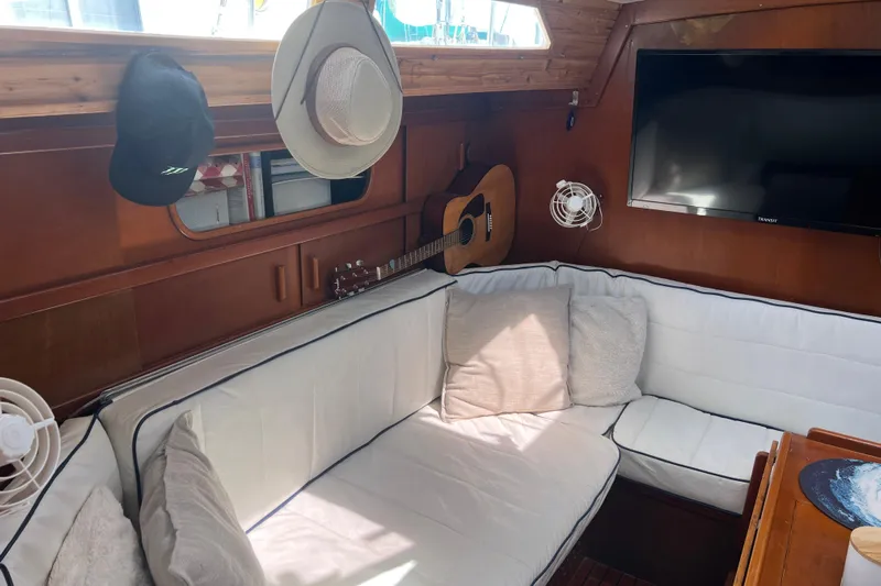 Hobo Tiempo Yacht Photos Pics Cozy interior of 1986 Amel Mango yacht with guitar, hats, and cushions.