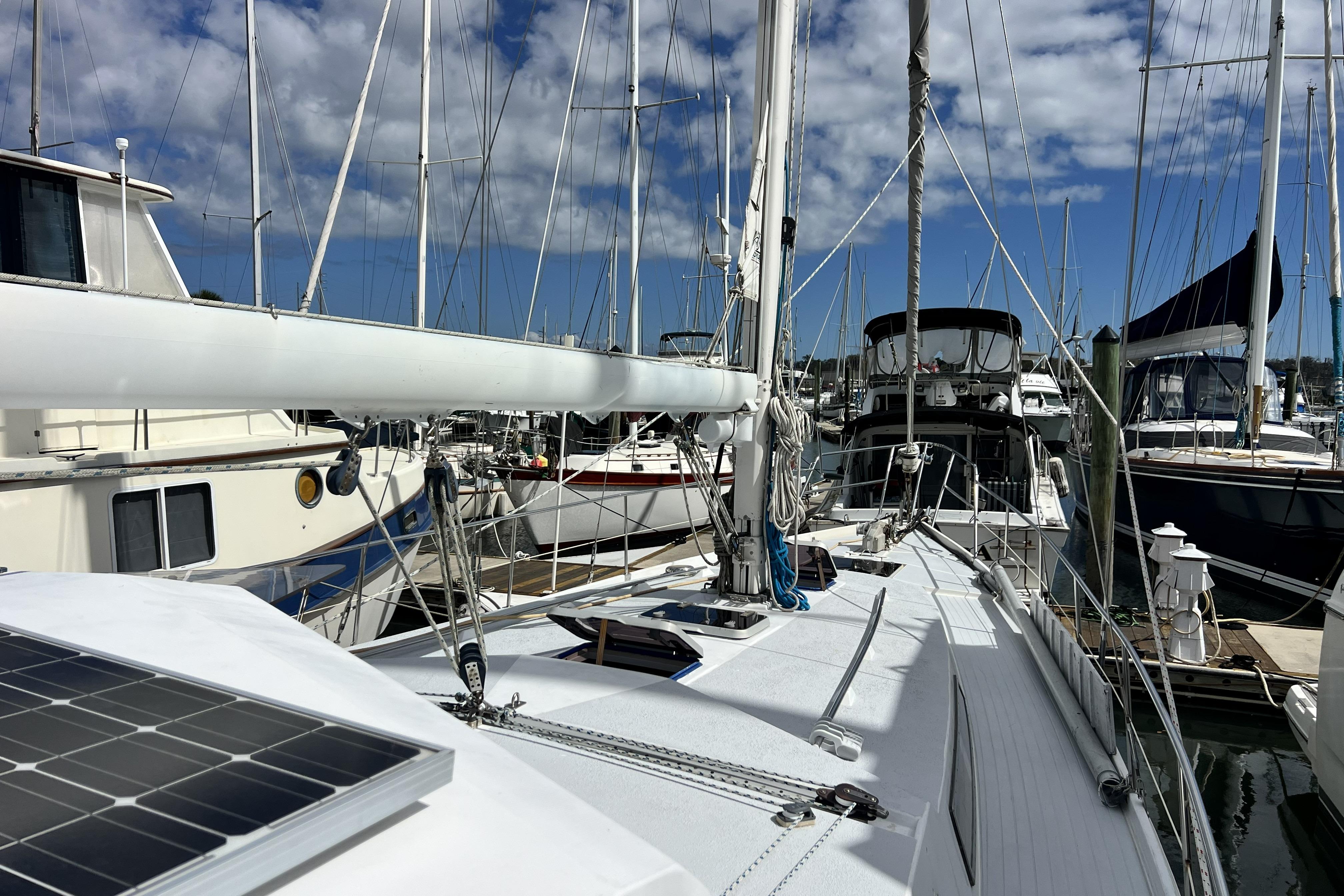 Sailboats docked at marina, featuring 1986 Amel Mango with solar panel.