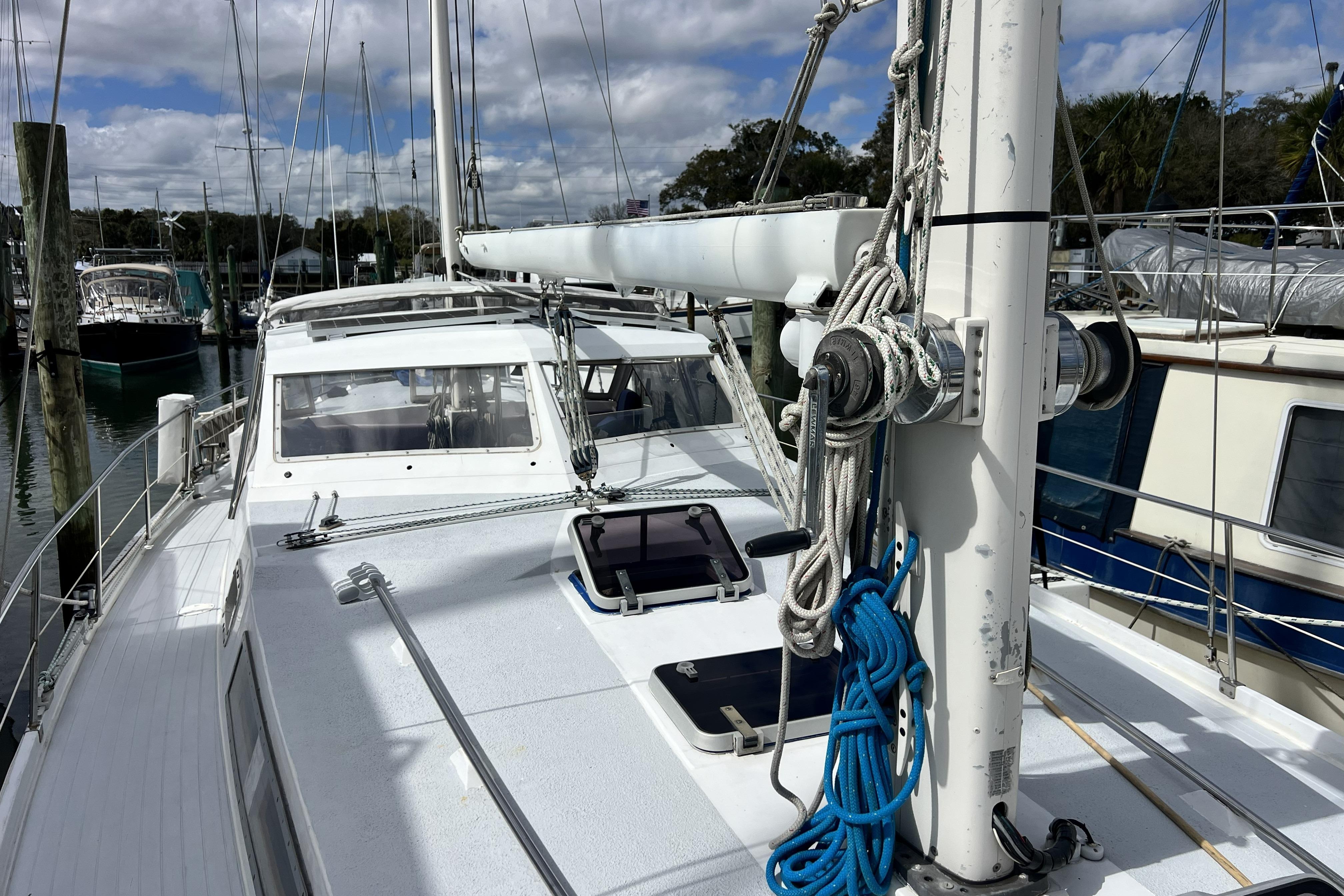 1986 Amel Mango sailboat docked, featuring deck and mast details under cloudy sky.