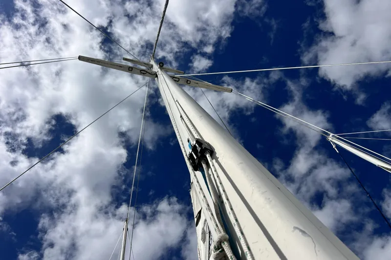 Hobo Tiempo Yacht Photos Pics Sailboat mast of 1986 Amel Mango against a cloudy blue sky.