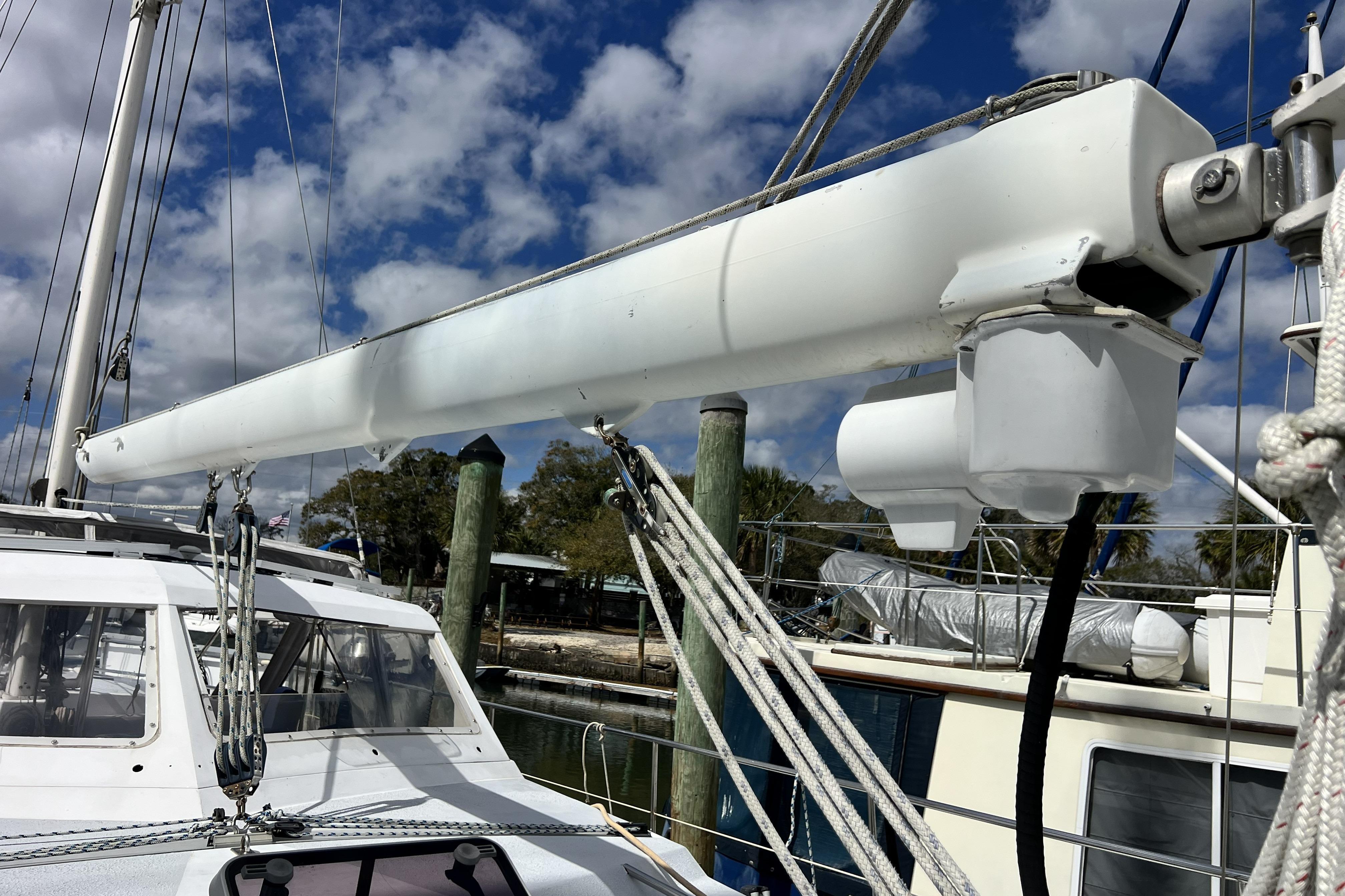1986 Amel Mango sailboat mast and rigging against a cloudy sky.