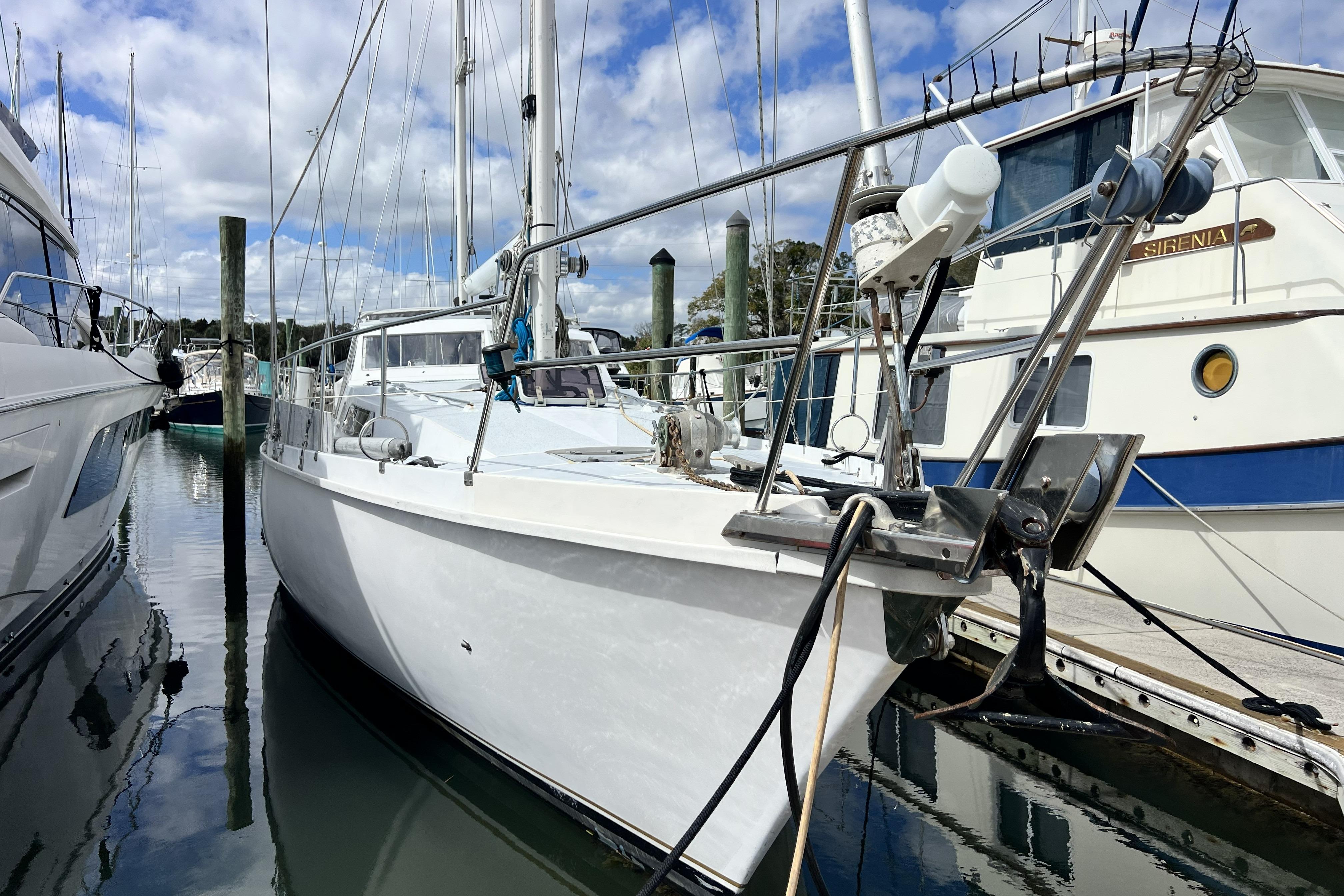 1986 Amel Mango sailboat docked in marina, surrounded by other boats.