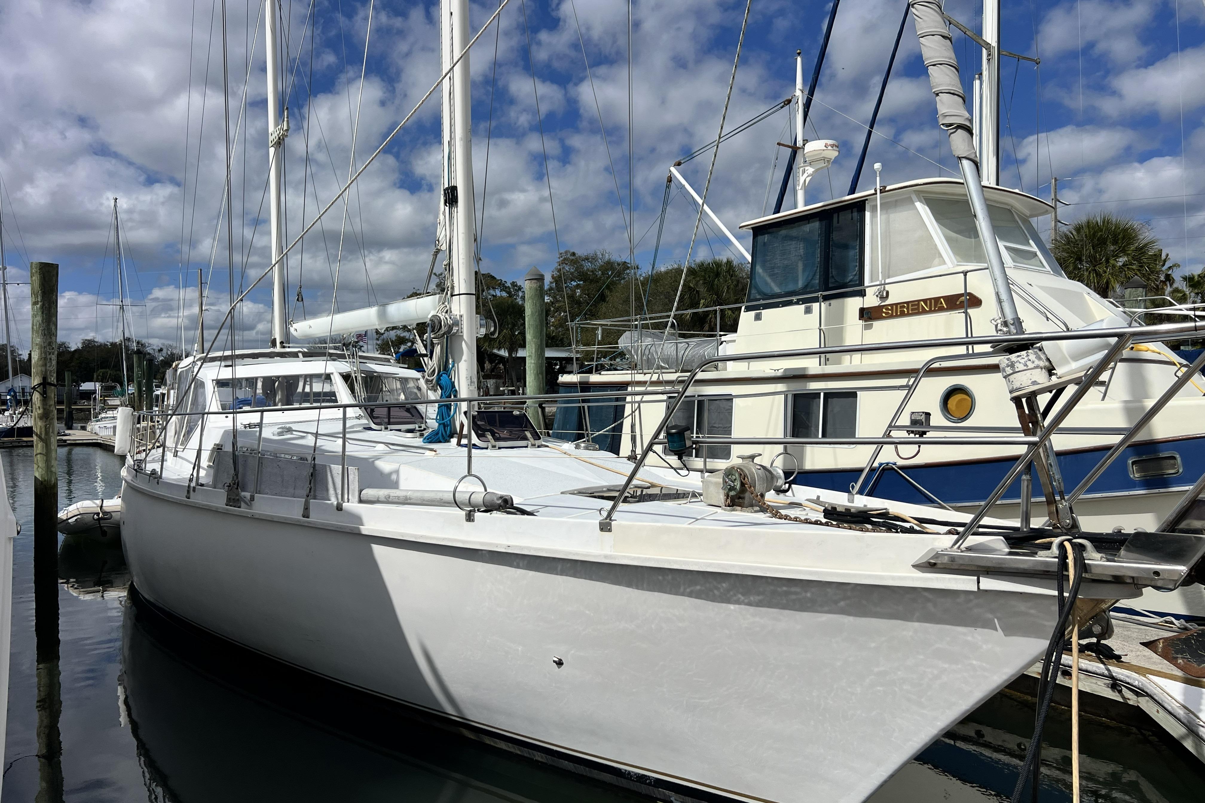 1986 Amel Mango sailboat docked at marina under cloudy sky.
