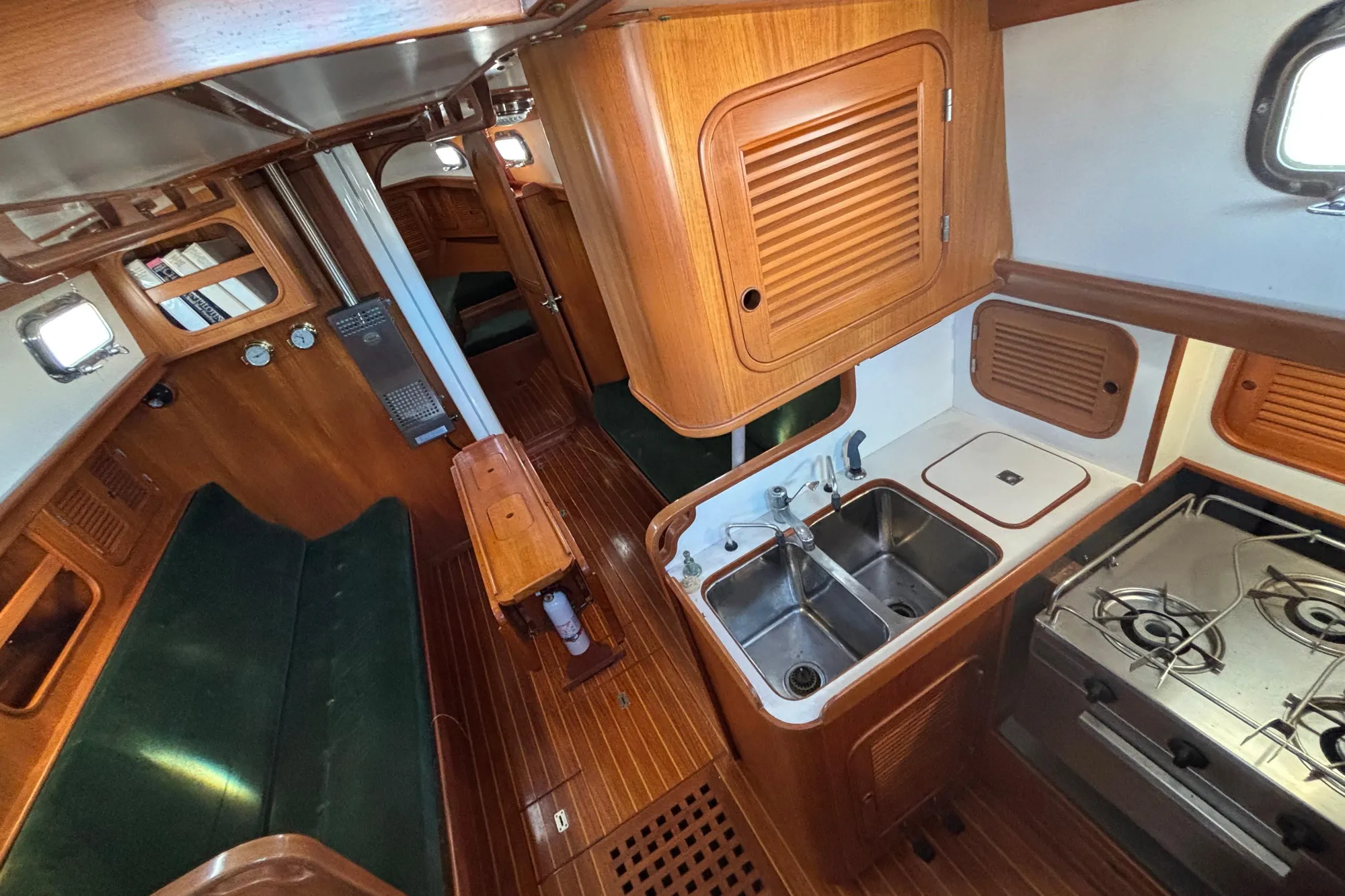 Interior of 1985 Mason 33 sailboat with wooden cabinetry and compact kitchen area.
