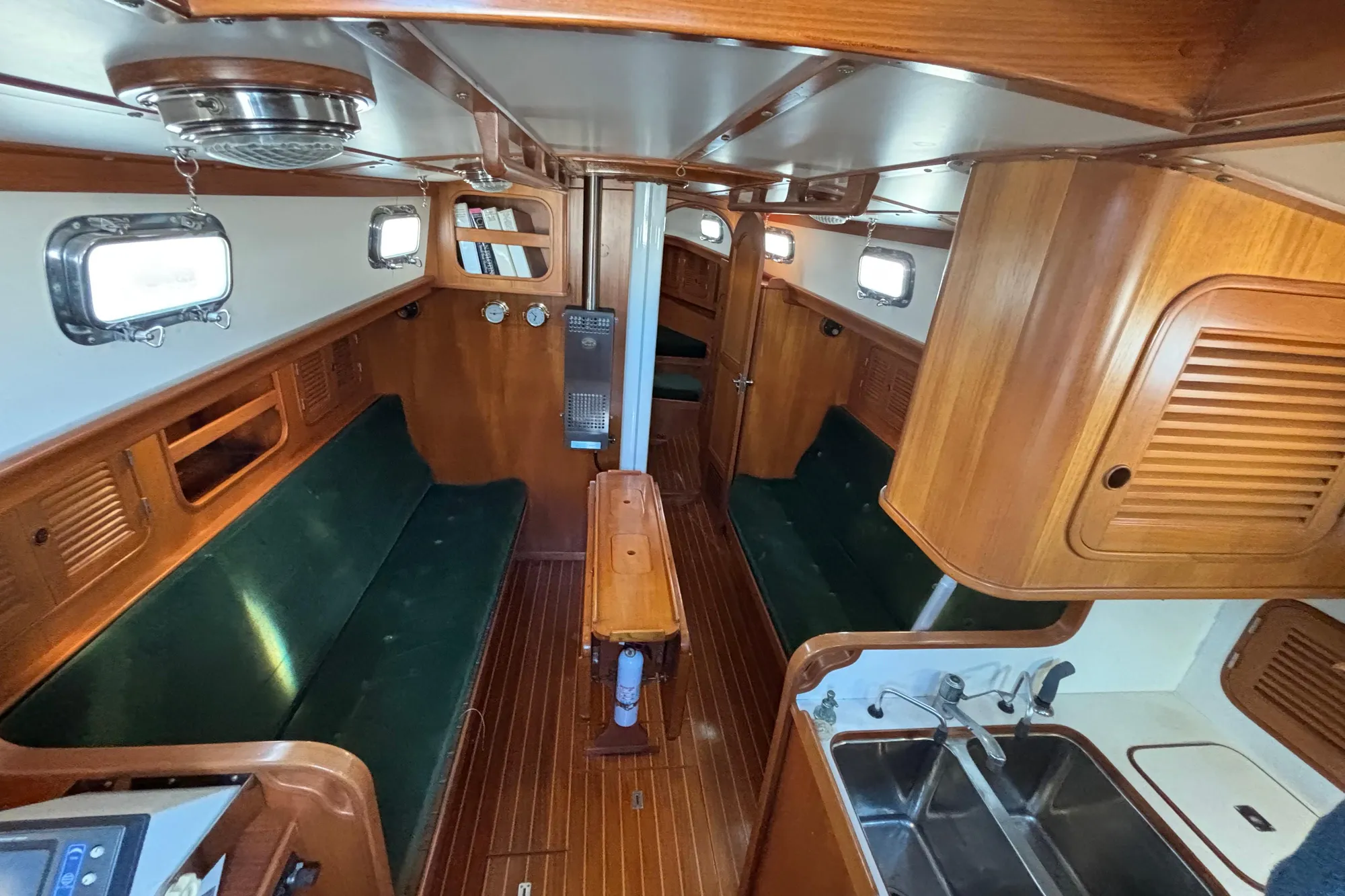 Interior of 1985 Mason 33 sailboat with wood finish and green seating.