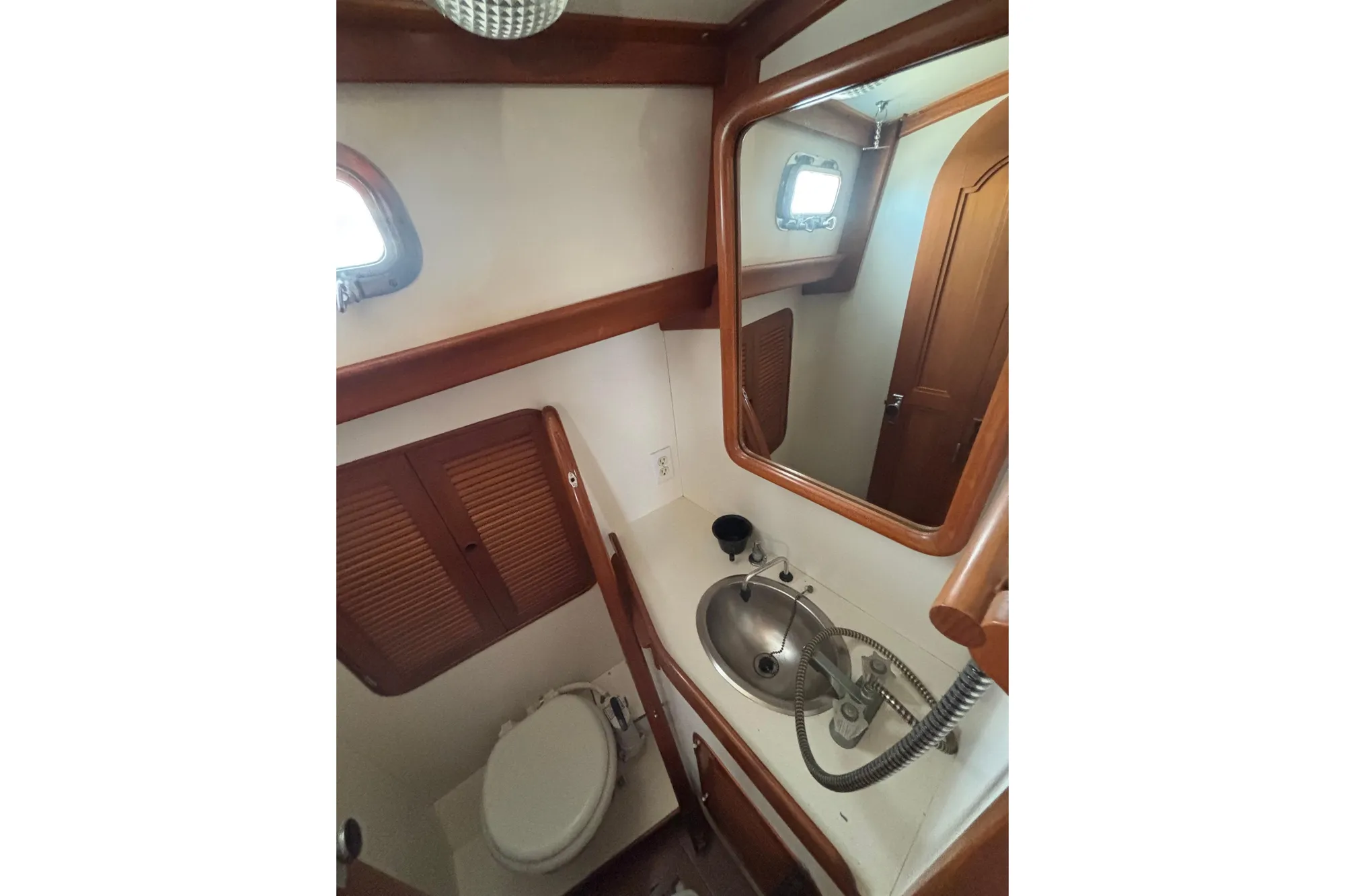 Compact bathroom in 1985 Mason 33 boat with sink, mirror, and wooden accents.