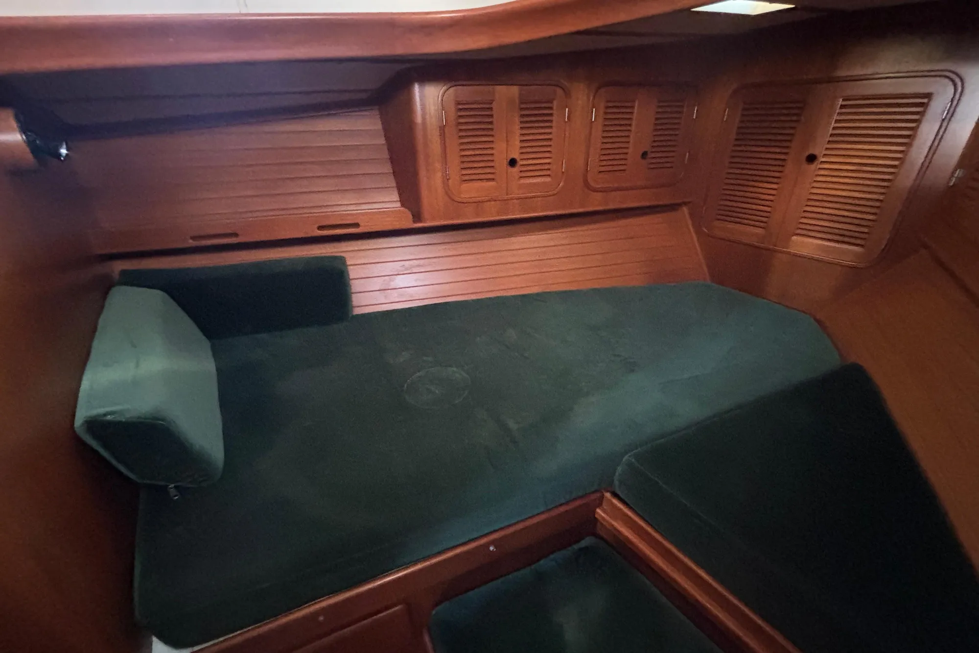 Cozy cabin interior of 1985 Mason 33 sailboat with green cushions and wooden paneling.