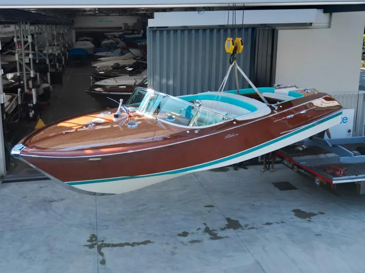 Turquoise Yacht Photos Pics 1974 Riva Aquarama Special boat suspended in a workshop, showcasing classic wooden design.