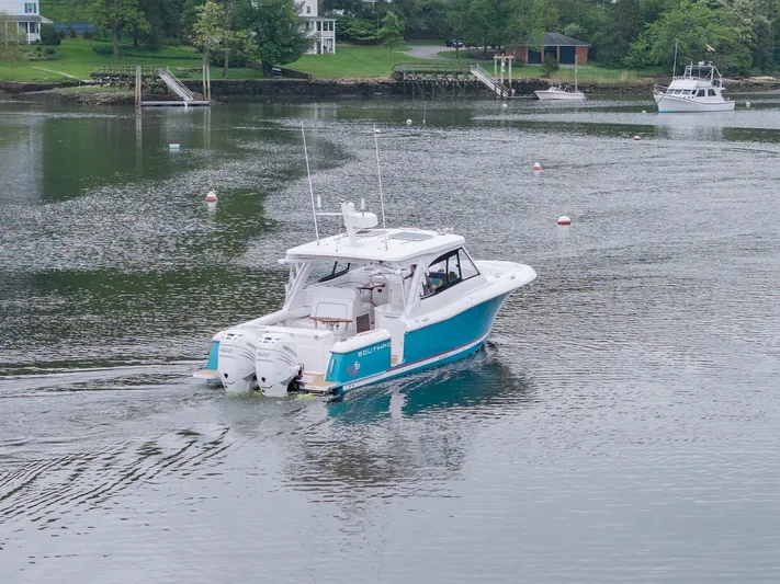 Even Flow Yacht Photos Pics 2021 Southport 33 DC boat cruising on a calm lake with scenic background.