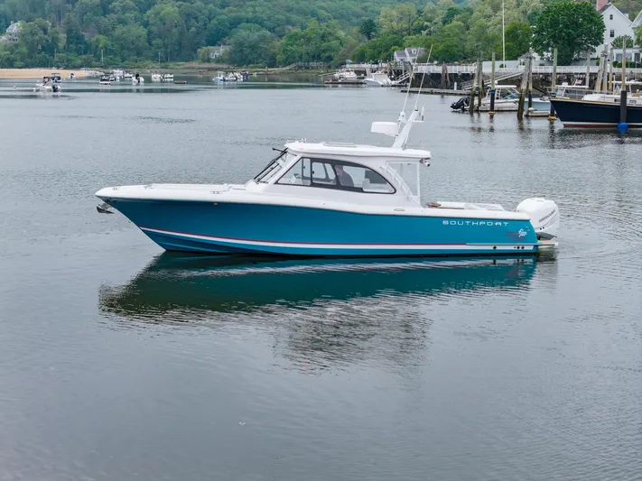 Even Flow Yacht Photos Pics 2021 Southport 33 DC boat on calm water, surrounded by lush greenery and docks.