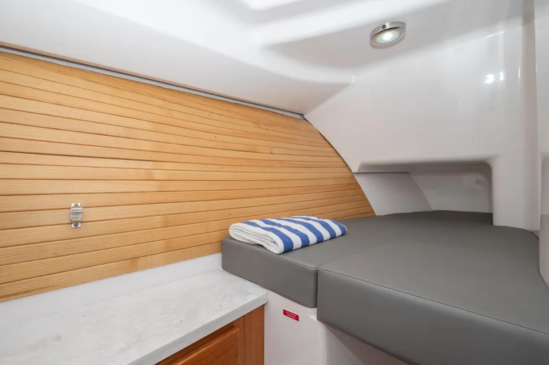Even Flow Yacht Photos Pics 2021 Southport 33 DC cabin interior with wooden paneling and cushioned bed.