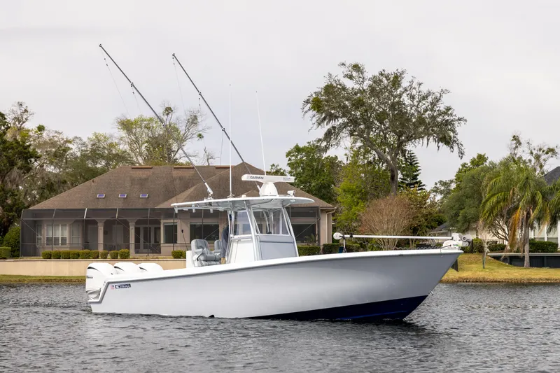  Yacht Photos Pics 2022 Contender 35 ST boat on a calm lake near a house.