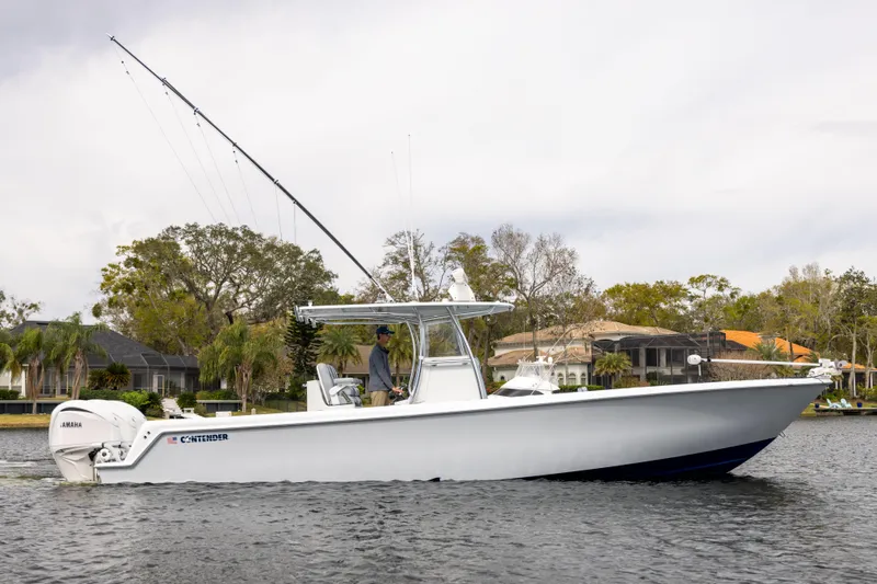  Yacht Photos Pics 2022 Contender 35 ST boat cruising on a calm waterway, surrounded by trees and houses.