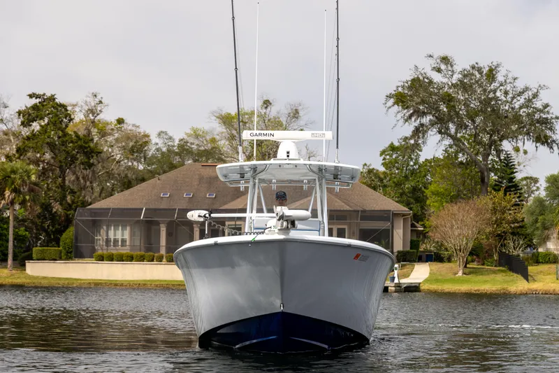  Yacht Photos Pics 2022 Contender 35 ST boat on calm water, with a house and trees in the background.