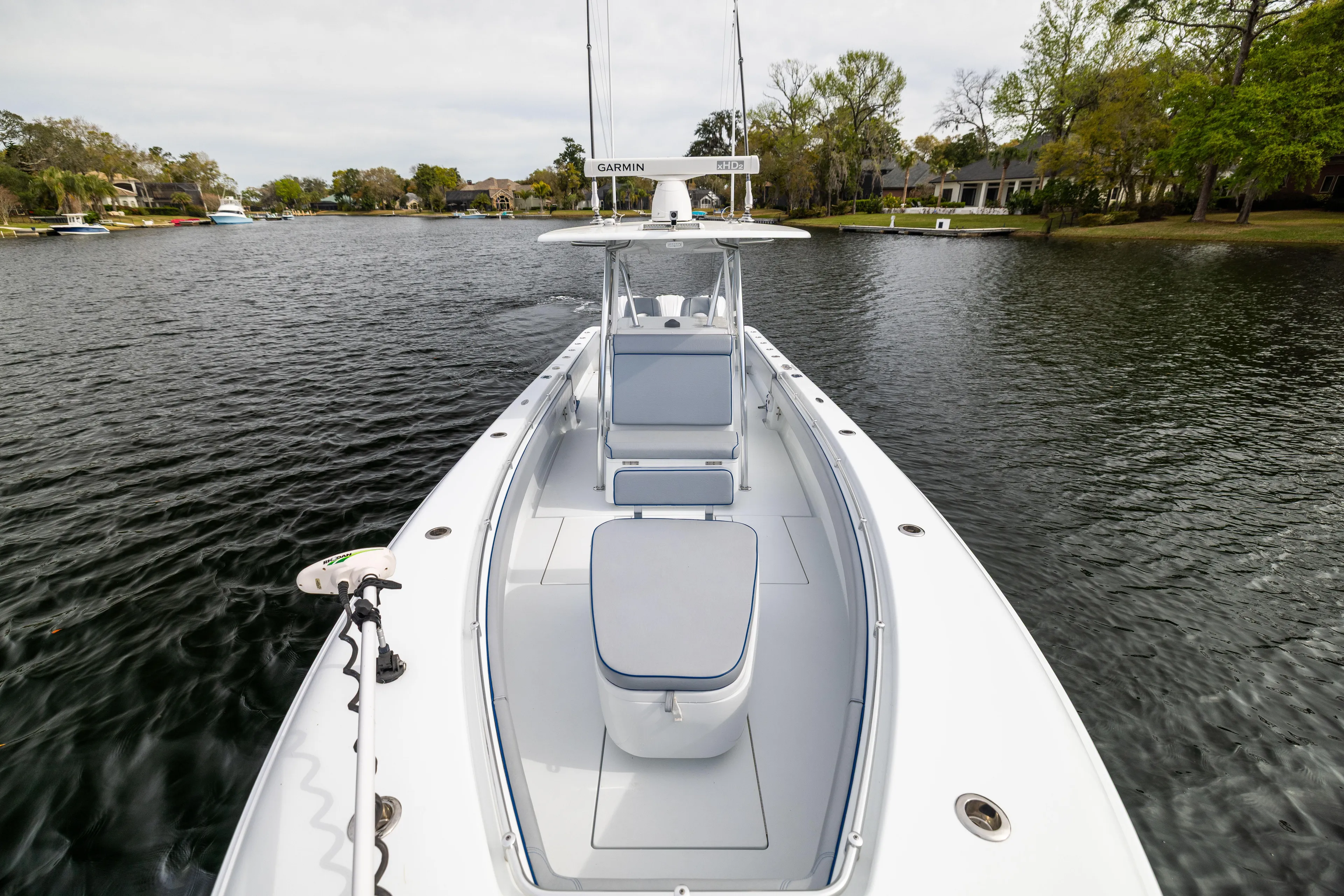  Yacht Photos Pics 2022 Contender 35 ST boat on a calm lake, surrounded by trees and houses.