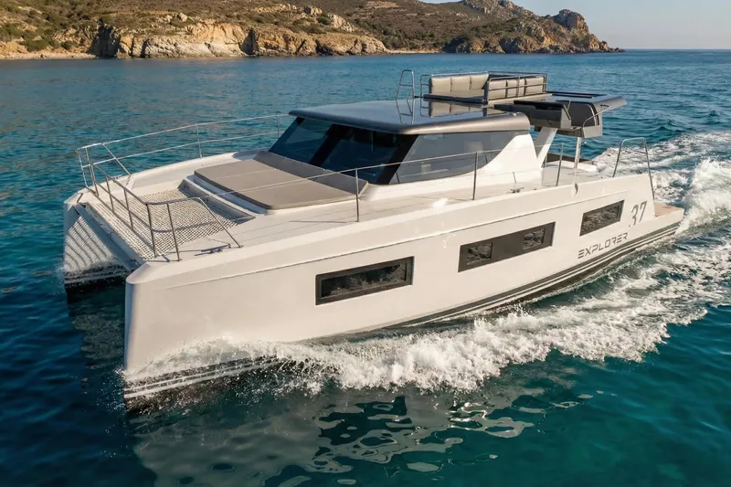  Yacht Photos Pics 2025 Aventura 37 Trawler cruising in clear blue waters near rocky coastline.