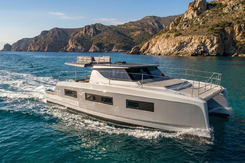  Yacht Photos Pics 2025 Aventura 37 Trawler cruising near rocky coastline in clear blue waters.