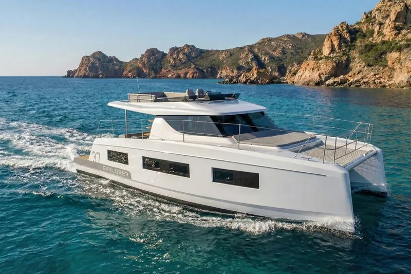  Yacht Photos Pics Aventura 37 Trawler 2025 cruising near rocky coastline in clear blue waters.