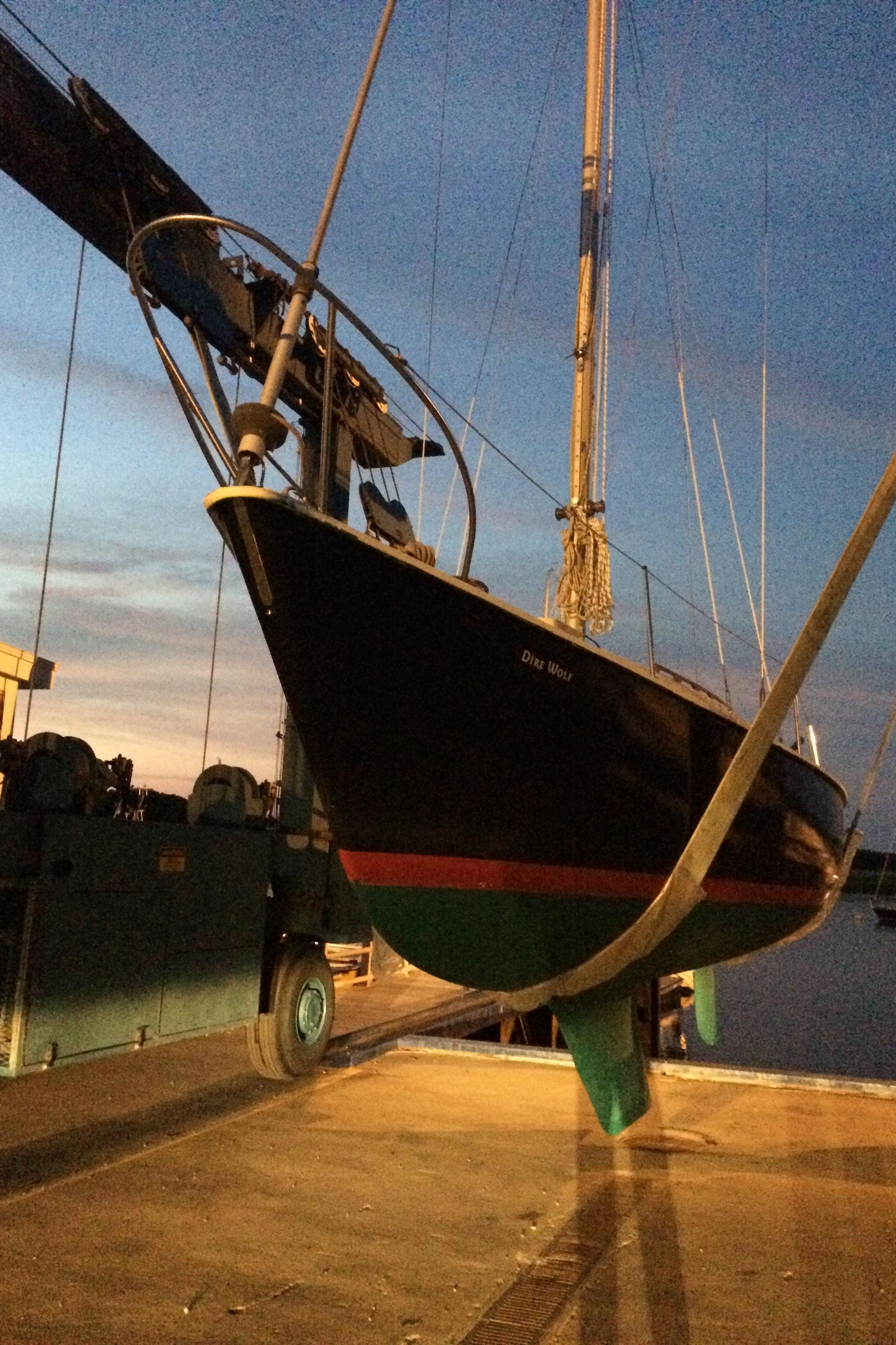 1974 Pearson 30 sailboat being lifted at sunset in a marina.