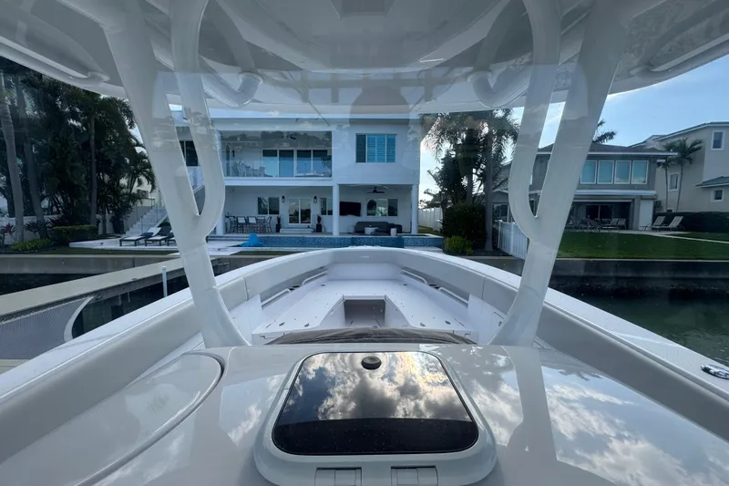 High Steaks Yacht Photos Pics 2024 Jupiter 38 HFS boat docked near waterfront homes, reflecting sky and clouds.