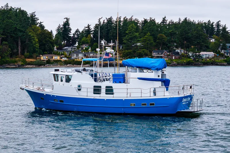Single Star Yacht Photos Pics 1978 Hidden Harbor Custom Trawler on water, surrounded by lush greenery and coastal homes.