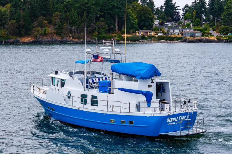 Single Star Yacht Photos Pics 1978 Hidden Harbor Custom Trawler cruising near a forested shoreline.