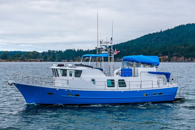 Single Star Yacht Photos Pics 1978 Hidden Harbor Custom Trawler cruising on scenic waters with forested hills in the background.