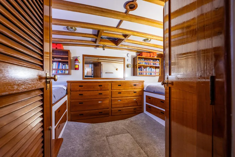 Single Star Yacht Photos Pics Cozy 1978 Hidden Harbor Custom Trawler cabin with wooden drawers, bookshelves, and carpeted floor.