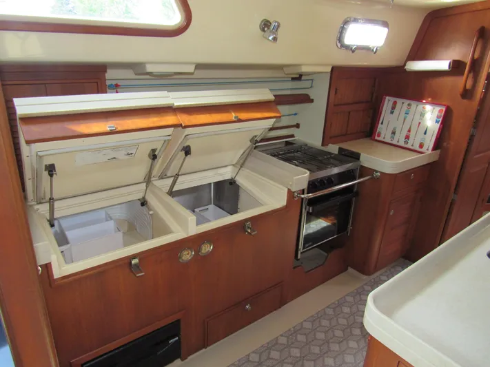 Priva Sea Yacht Photos Pics 2003 Island Packet 485 yacht kitchen with open storage, stove, and wooden cabinetry.