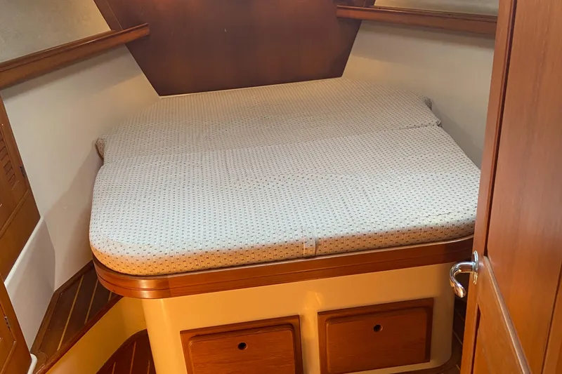 Priva Sea Yacht Photos Pics Cozy cabin bed in 2003 Island Packet 485 sailboat, featuring wooden accents and storage drawers.