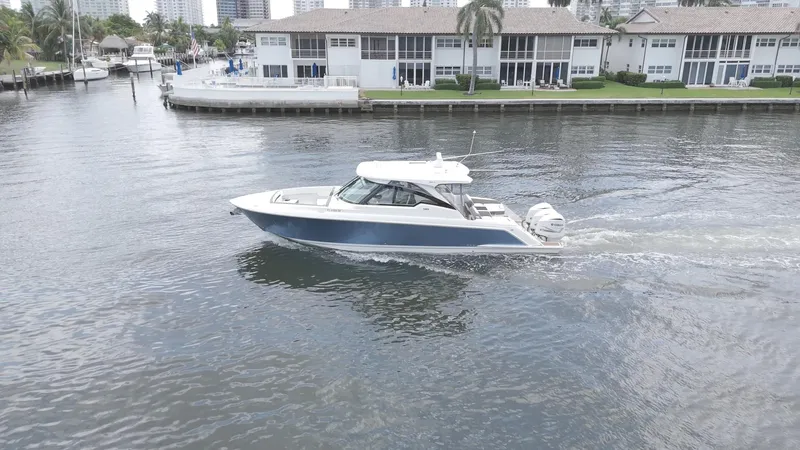  Yacht Photos Pics 2021 Tiara Sport 38 LX boat cruising on a calm waterway near waterfront homes.