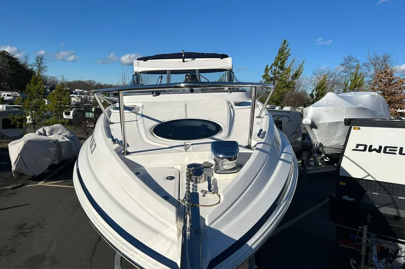  Yacht Photos Pics 2024 Regal 28 Express boat in outdoor storage, surrounded by trees and covered vehicles.
