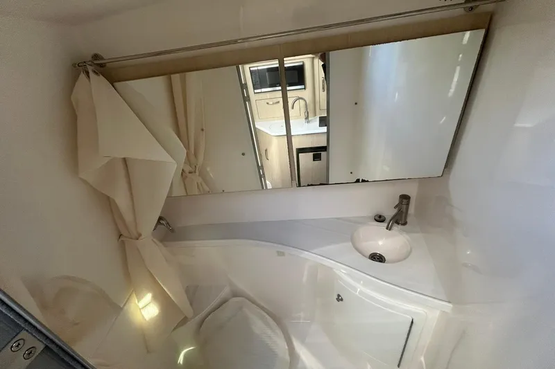  Yacht Photos Pics 2024 Regal 28 Express bathroom with mirror, sink, and curtain.