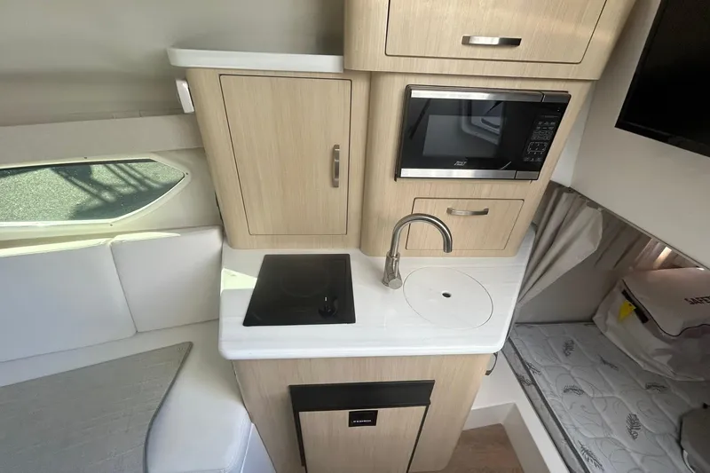 Yacht Photos Pics 2024 Regal 28 Express boat interior with kitchenette, featuring microwave, sink, and stove.