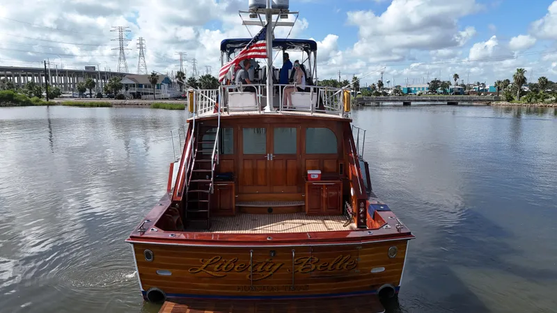 Liberty Belle Yacht Photos Pics 1980 Bertram 58 Convertible Custom yacht on calm water, rear view with American flag.