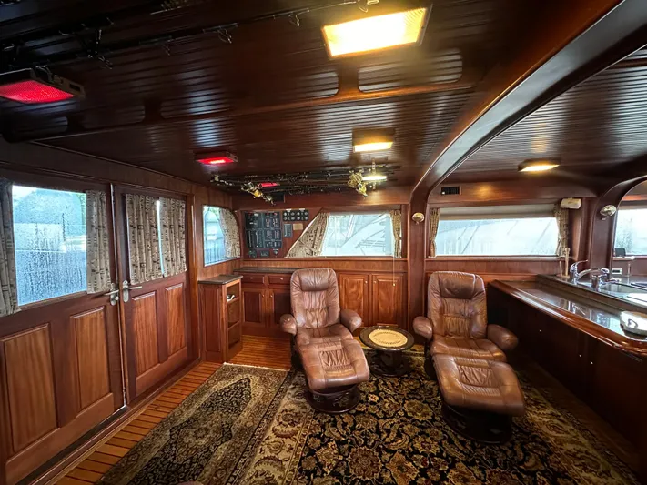 Liberty Belle Yacht Photos Pics Luxurious interior of 1980 Bertram 58 Convertible Custom yacht with leather chairs and wood paneling.