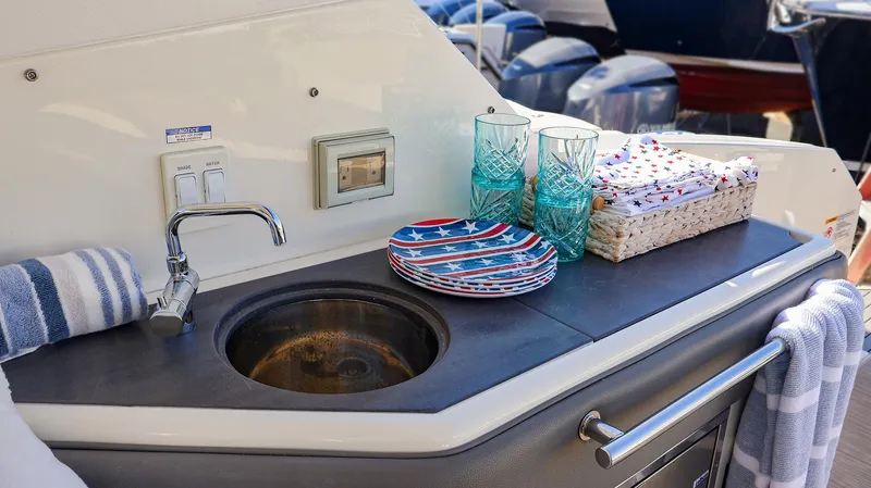 4743jg Yacht Photos Pics Outdoor sink area on 2021 Sea Ray 320 Sundancer yacht with plates and glasses.