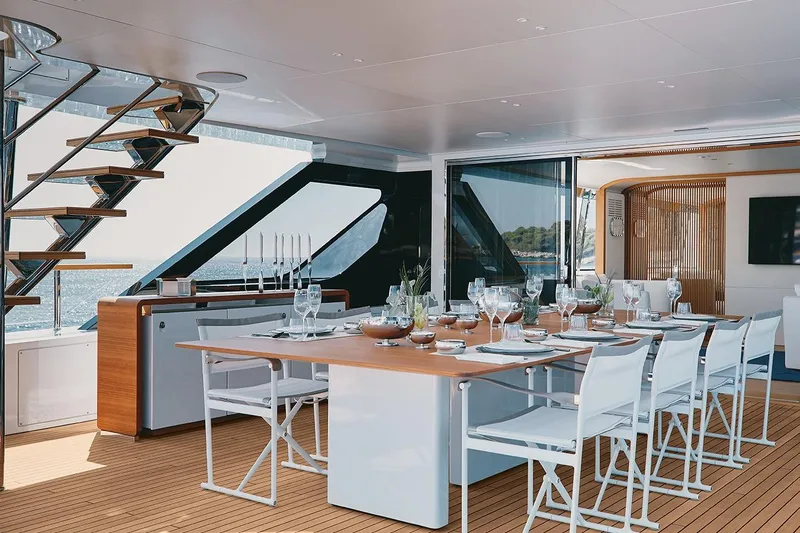 Koju Yacht Photos Pics Luxurious dining area on 2022 Benetti Motopanfilo yacht with elegant table setting and modern design.